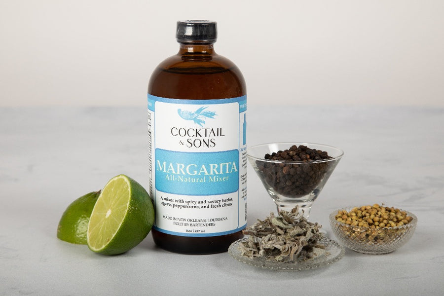 Cocktail and sons Margarita mixer with some of it's main flavoring agents; including peppercorns, fresh limes, and savory herbs 