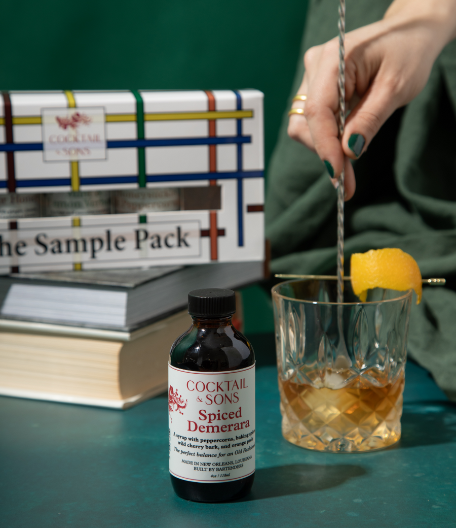 Cocktail and Sons Spiced Demerara syrup flavoring an old fashioned in front of The Sample Pack 
